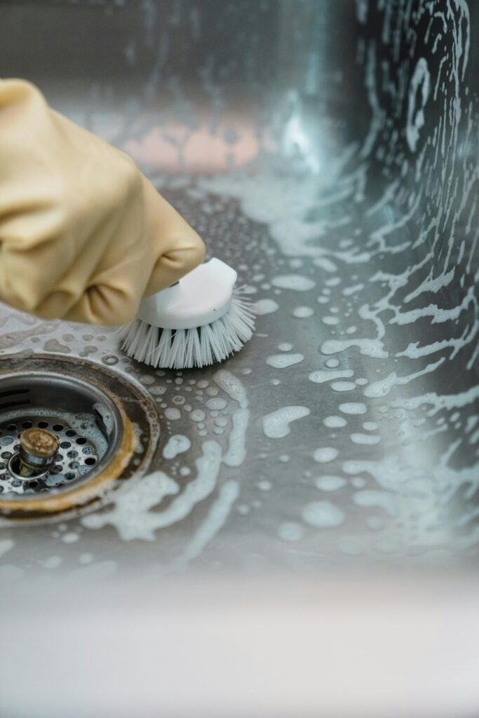Deep Cleaning Houston service scrubbing a kitchen sink and removing buildup